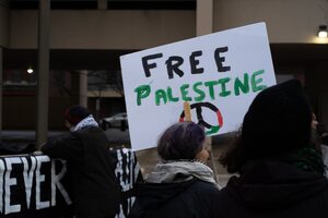 Attendees of the demonstration and vigil in solidarity with Palestine, held in front of the James M. Hanley Federal Building, carry signs that say “Free Palestine” and other calls for peace and justice.